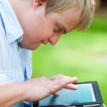 Young man with Down Syndrome reading a tablet