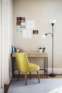 A desk, a chair, a lamp, with posters on the wall
