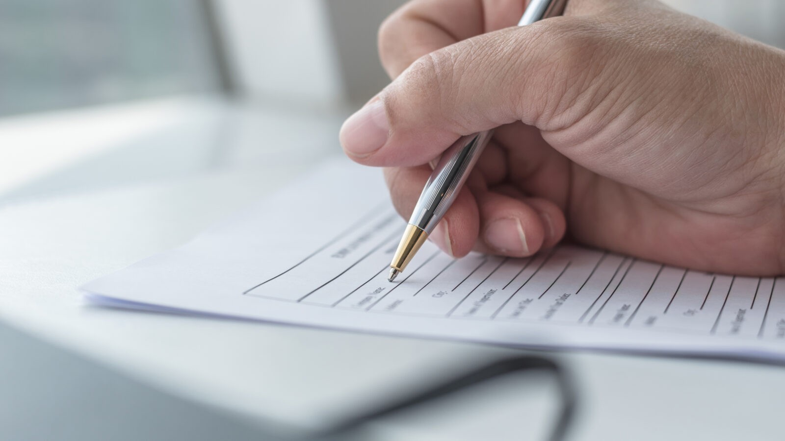 hand holding a pen and filling out a form